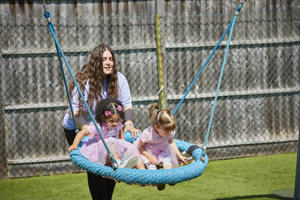 Staff pushing children on swing